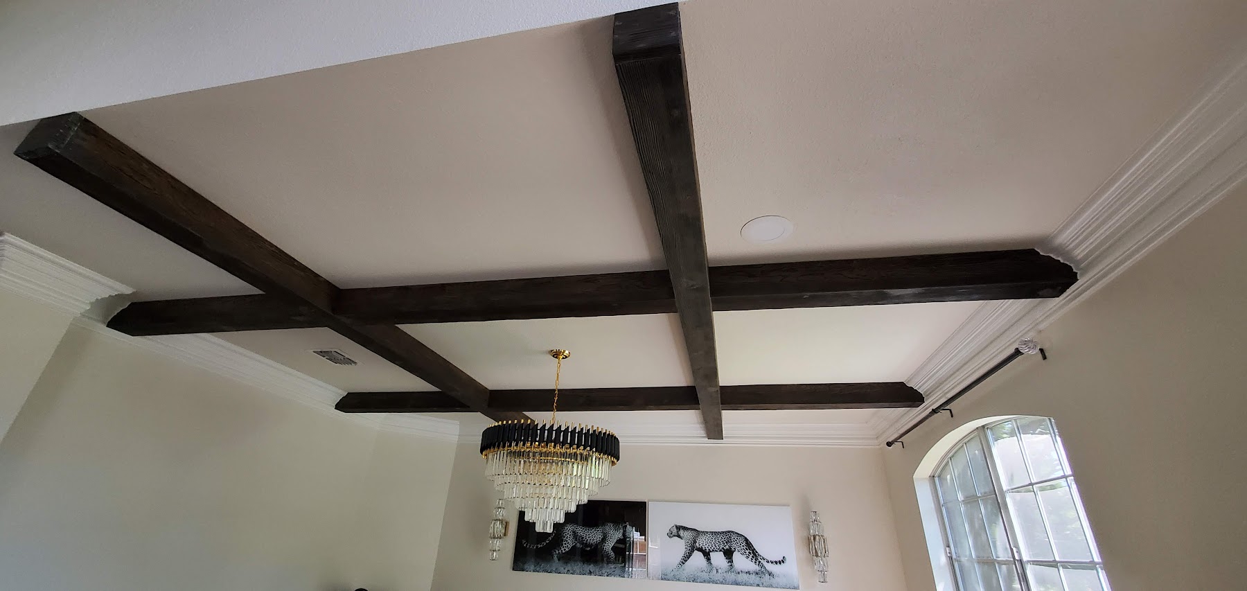 Custom ceiling beams and chandelier detail in a completed dining room