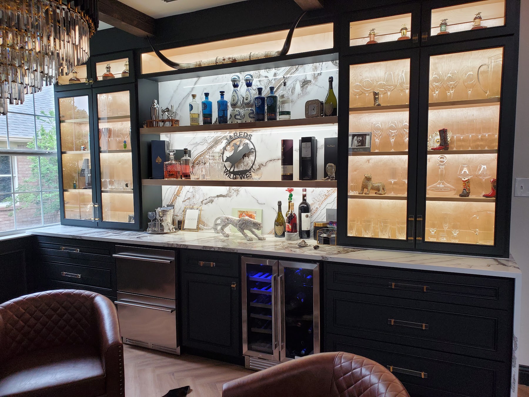 Completed custom black built-ins with illuminated shelving and stone countertop