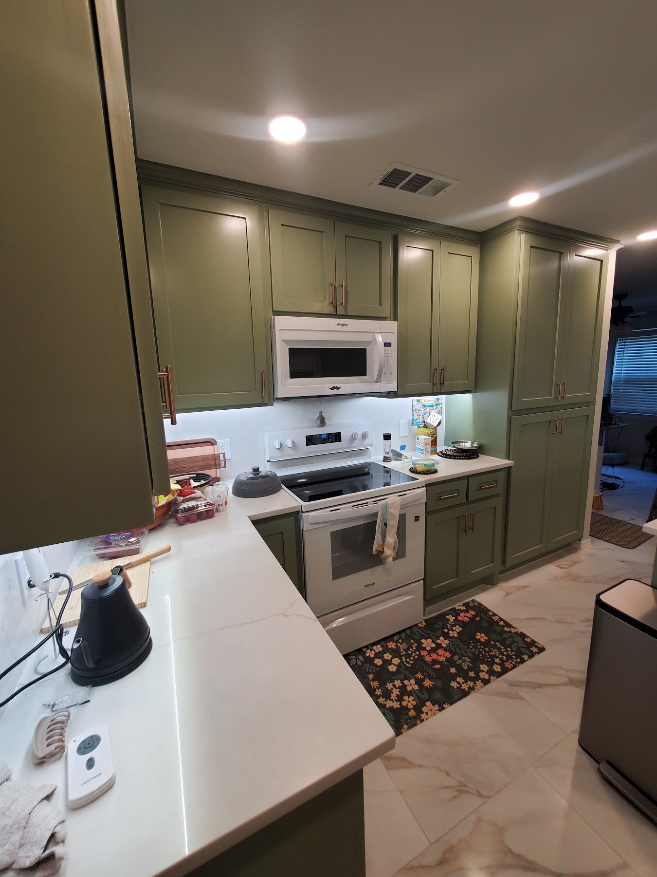 Green kitchen cabinets with bright counters and updated finishes