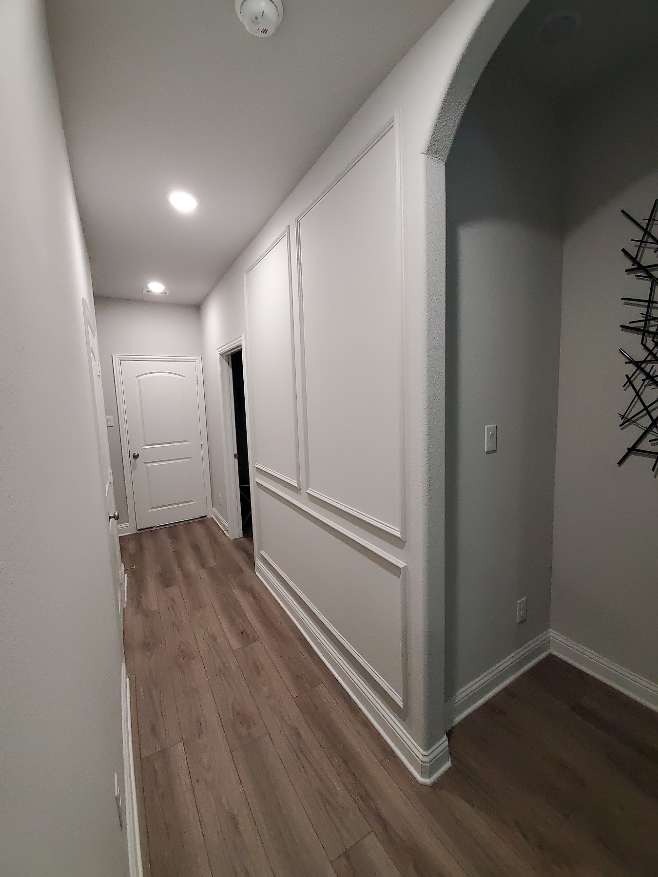 Finished hallway with decorative wall paneling and wood flooring
