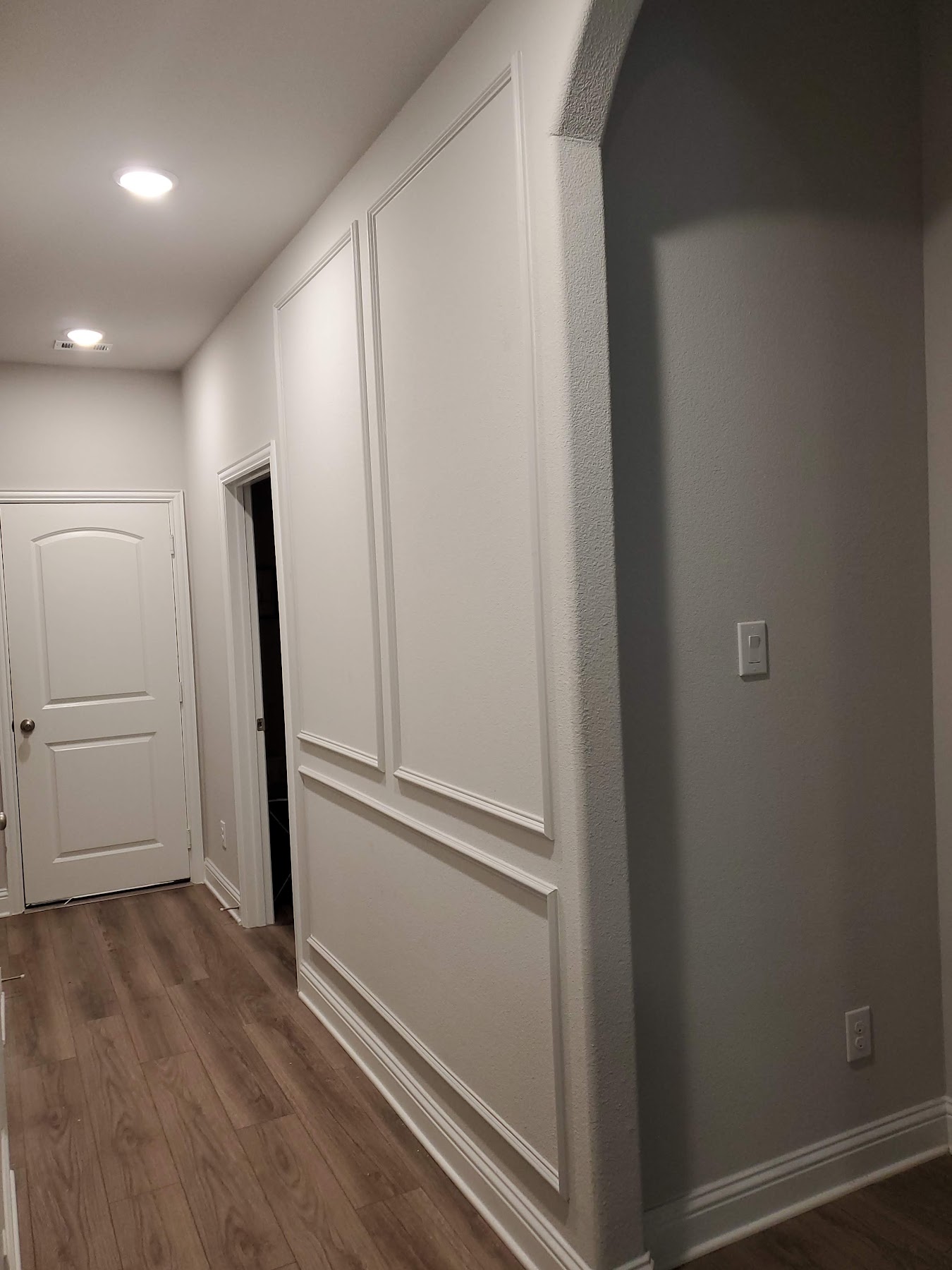 Finished hallway with continuous wall paneling and recessed lighting