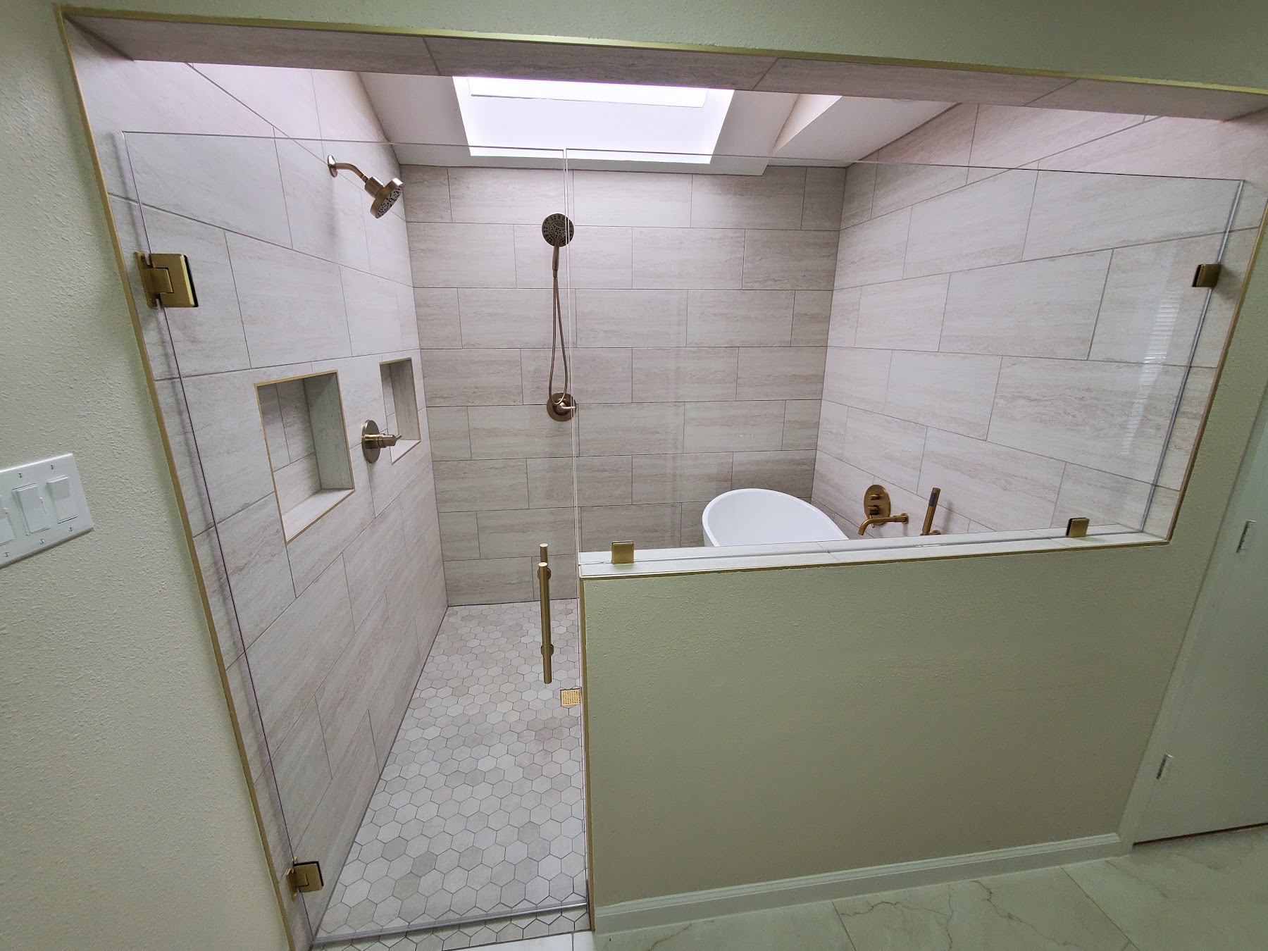 Completed walk-in shower with tile, niche, and glass enclosure