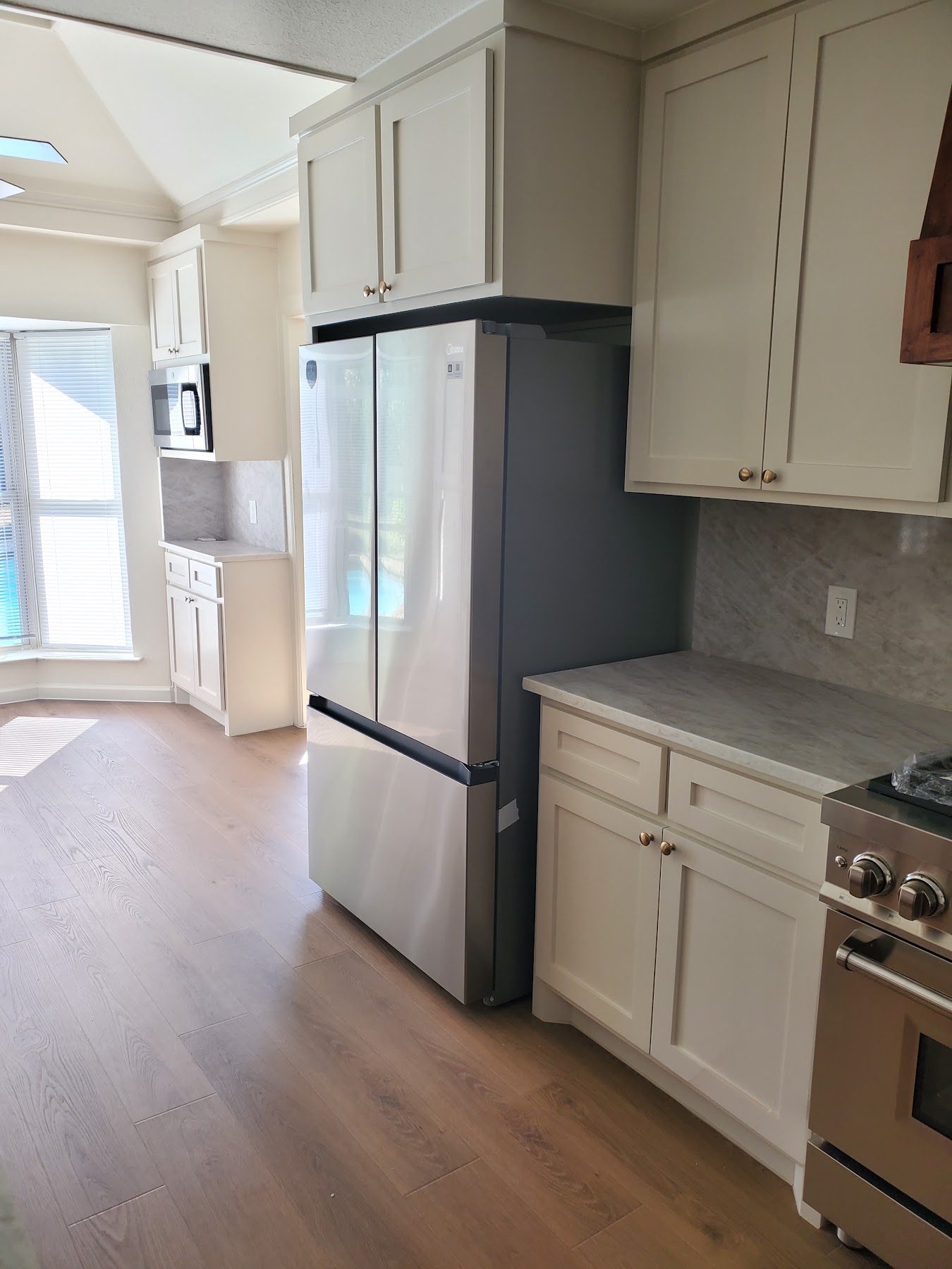 Completed kitchen range wall with cabinetry and wood hood